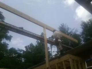 Carpenter setting a ridge beam over a new addition frame — Ice Dam Removal by Roofing Brothers in Hiltons