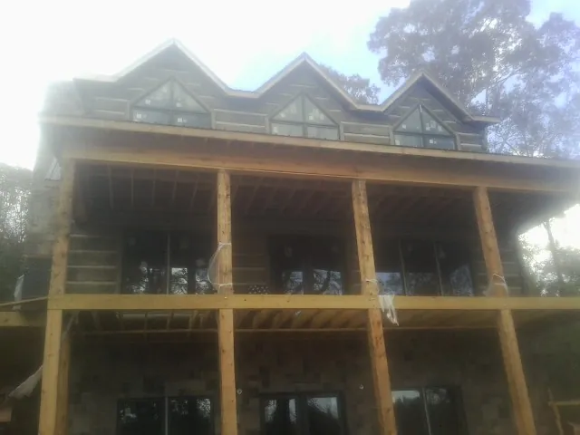 Dormers and porch framing on a large log home under construction — Roof Coating work by our crew in Hiltons