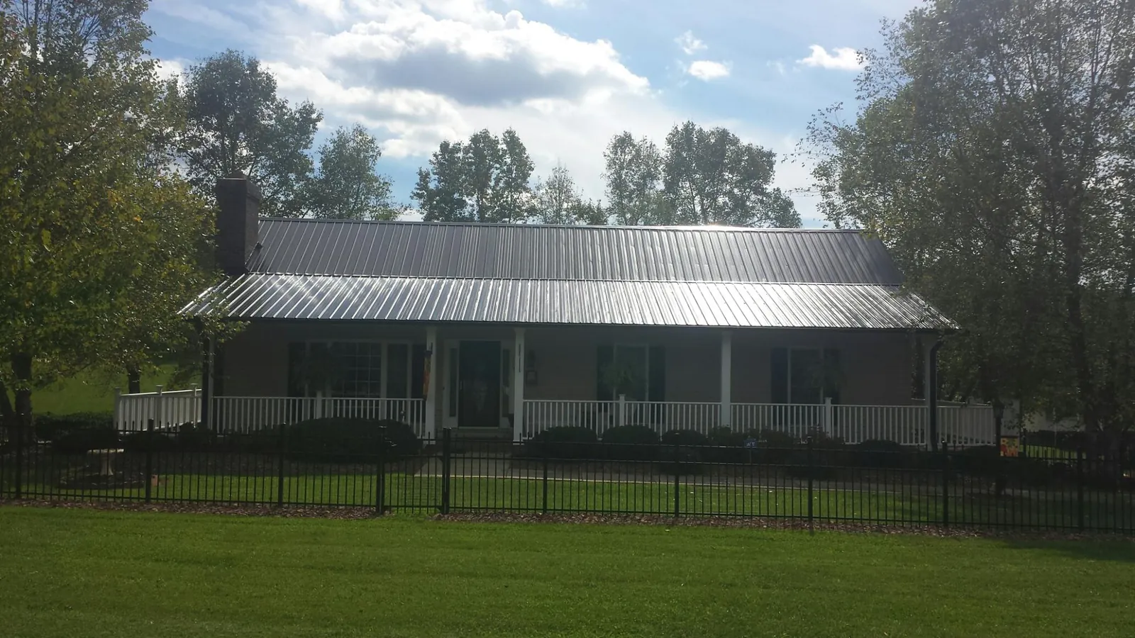 Gray metal roof on a brick ranch with a full width front porch — Gutter Guard Installation work by our crew in Hiltons