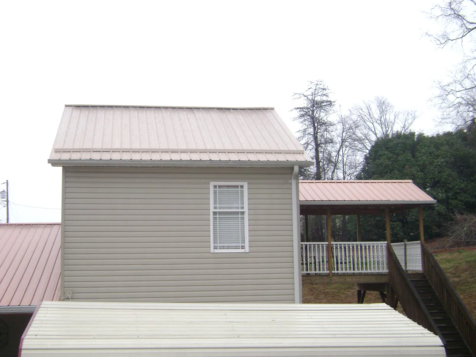 Tan metal roofs on a two story addition and attached porch, from a Roof Replacement job in Hiltons