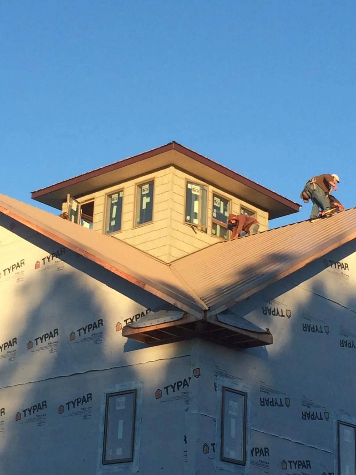 Roofers working around a rooftop cupola on a new metal roof at sunset — Roof Waterproofing in Hiltons by Roofing Brothers